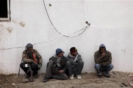 Libyan rebels sit at a checkpoint outside the city of Ajdabiyah, March 13, 2011.