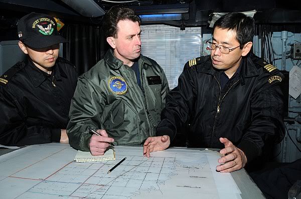 Capt. Jim Morgan, middle, commander of Destroyer Squadron 7, coordinates search and rescue efforts with Japan Maritime Self-Defense Force Capt. Iwasaki, commander of Escort Flotilla 1, aboard the aircraft carrier USS Ronald Reagan (CVN 76).