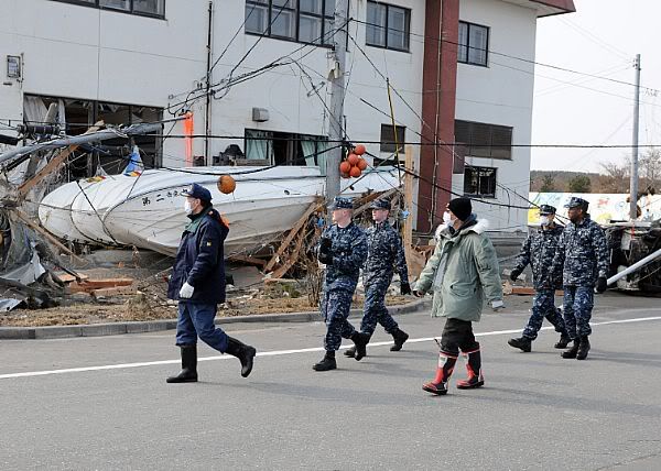 Masayoshi Sawaguchi, director of the Department of Policy and Finance for Misawa City, guides Sailors assigned to Naval Air Facility Misawa to an area at the Misawa Fishing Port in need of clean-up.