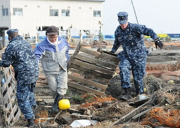 Chief Naval Air Crewmen Kyle Wilkinson, right, from Baldwinsville, N.Y., assigned to Naval Air Facility Misawa, helps remove debris during a cleanup effort at the Misawa Fishing Port.
